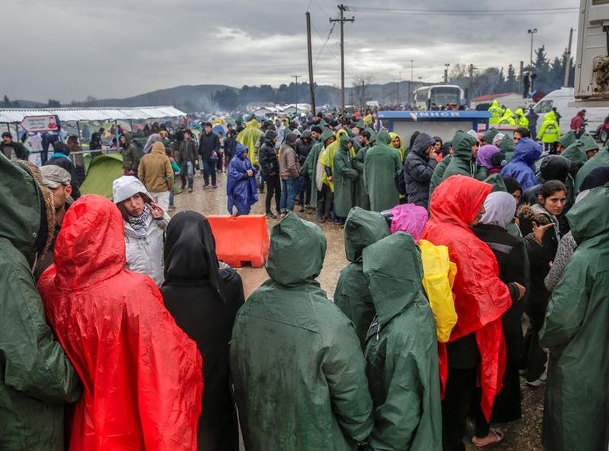  Refugiados y migrantes esperan cola bajo la lluvia para recibir comida mientras esperan en un campo de refugiados cerca de Idomeni (Grecia) para cruzar la frontera. 