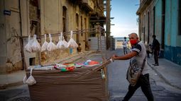 Un vendedor ambulante con una máscara como medida de precaución contra la propagación del coronavirus empuja su carro por una calle en La Habana, Cuba, el lunes 31 de agosto de 2020.