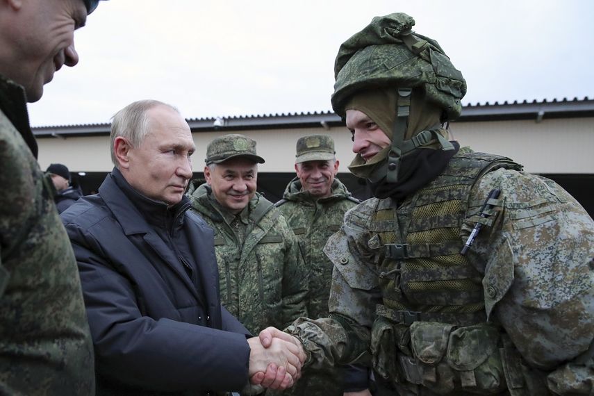 El presidente de Rusia, Vladimir Putin estrecha la mano de un soldado durante una visita a un centro de instrucción militar en el Distrito Militar Occidental para reservistas movilizados, mientras el ministro ruso de Defensa, Sergei Shoigu, en el centro, sonríe, en la región de Ryazan, Rusia, el jueves 20 de octubre de 2022.