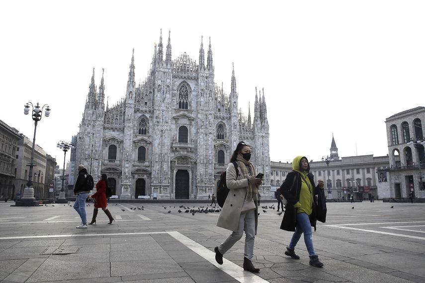 Una mujer con mascarilla pasa ante la catedral gótica del Duomo en Milán, Italia, el domingo 23 de febrero de 2020. 