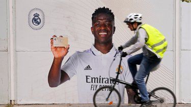 Un ciclista pasa frente a un afiche de Vinicius Junior, el delantero brasileño del Real Madrid, frente al estadio Santiago Bernábeu, el lunes 22 de mayo de 2023 en Madrid.