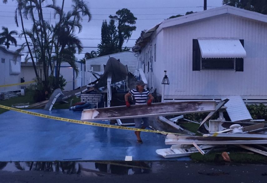 Una mujer mueve los escombros que dejó un tornado asociado al paso de la tormenta tropical Philippe en Boyton Beach, Florida.