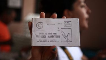Una mujer muestra una libreta de abastecimiento.