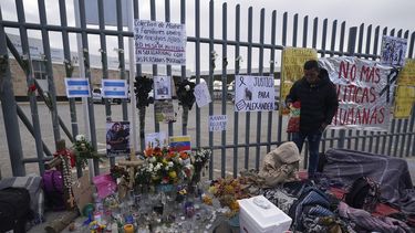 Un altar con velas y fotos cubre la cerca afuera del centro de detención de migrantes que fue el sitio de un incendio mortal, mientras los migrantes se despiertan después de pasar la noche en la acera en Ciudad Juárez, México, el jueves 30 de marzo de 2023.&nbsp;