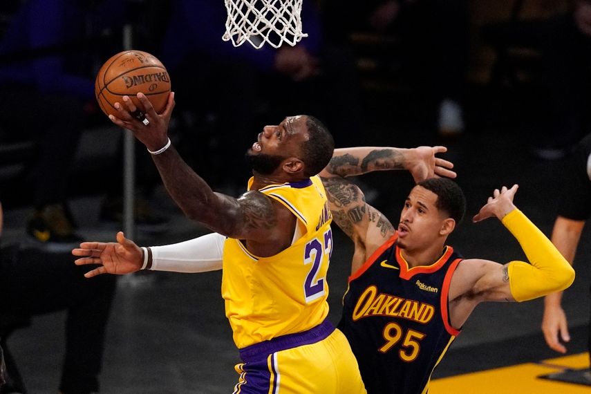 El jugador de los Lakers de Los Ángeles LeBron James (izquierda), lanza a canasta ante Juan Toscano-Anderson, de los Warriors de Golden State, en la primer mitad del juego de play-in de la Conferencia Oeste que enfrentó a ambos equipos, el 19 de mayo de 2021, en Los Ángeles.&nbsp;