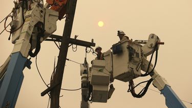 En esta fotografía del 9 de noviembre de 2018, trabajadores de la compañía Pacific Gas & Electric reparan el tendido eléctrico en Paradise, California. 
