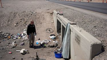 Mark Paulson, un funcionario local, sostiene latas de agua fría mientras revisa un campamento para indigentes, el miércoles 10 de julio de 2024, en Henderson, Nevada.