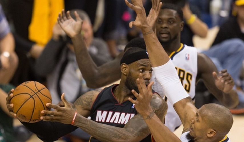 LeBron James (i) de los Heat de Miami intenta un pase contra David West (d) de los Pacers de Indiana, durante su partido de los Playoffs del Campeonato de la Conferencia Este de la NBA en el Bankers Life Fieldhouse.