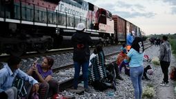 Migrantes observan un tren en marcha junto a las vías en las que esperan para subir a bordo de un vagón con el fin de dirigirse al norte de México, el 19 de septiembre de 2023, en Huehuetoca, México.