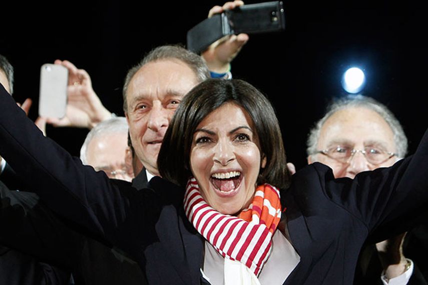 La socialista Anne Hidalgo (centro), sonríe, con el alcalde saliente Bertrand Delanoe a su espalda, durante un discurso después de anunciarse los resultados de la segunda vuelta de las elecciones municipales, en París.(Foto AP/Thibault Camus)