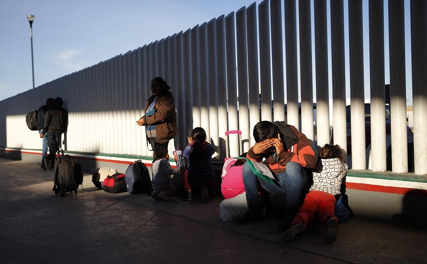 En esta imagen del 25 de enero de 2019, un migrante se sienta al lado de sus hijos mientras esperan a que les llamen para solicitar asilo en Estados Unidos, junto al muro fronterizo en Tijuana, México.
