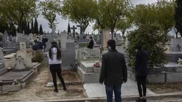 Familiares, con mascarillas respetan el protocolo de distancia social durante un entierro en un cementerio de Madrid, durante el brote del coronavirus, el 27 de marzo de 2020.&nbsp;