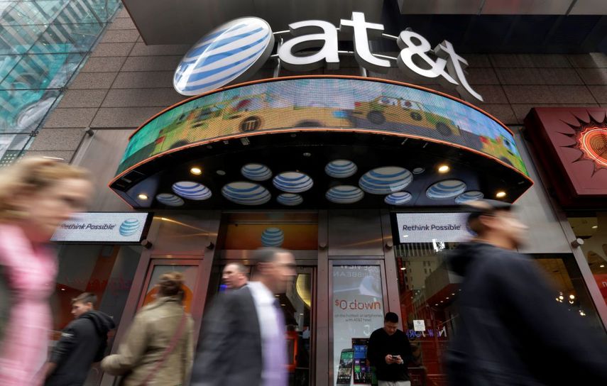 Unas personas caminan frente a una tienda de AT&T en Times Square, en Nueva York, el 21 de octubre de 2014.&nbsp; &nbsp;