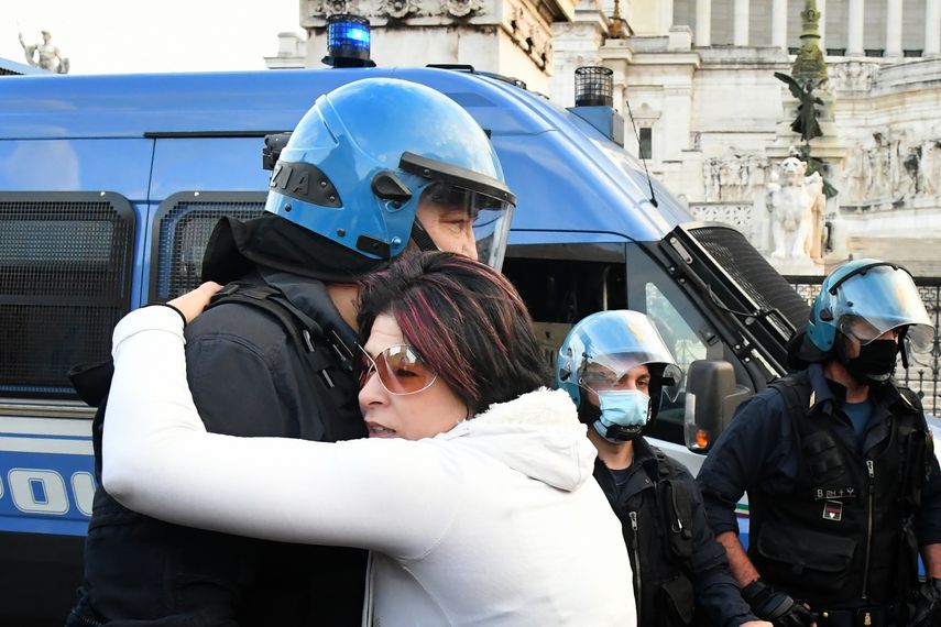 Un manifestante abraza a un oficial de policía en provocación el 15 de noviembre de 2020, en Roma, durante una manifestación antimáscaras y contra las restricciones del gobierno sobre la pandemia Covid-19.