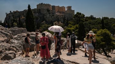 Turistas, algunos con paraguas, se reúnen frente a la Acrópolis de Atenas el 8 de julio de 2025.