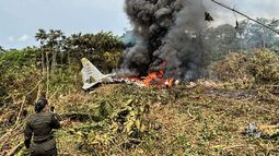 Llamas y una espesa columna de humo negro se elevan desde un avión Hércules de la Fuerza Aérea que se estrelló durante el despegue, mientras un miembro de la Policía colombiana permanece cerca, en Puerto Leguizamo, Colombia, cerca de la frontera sur con Ecuador, el 23 de marzo de 2026. Llamas y una espesa columna de humo negro se elevan desde un avión Hércules de la Fuerza Aérea que se estrelló durante el despegue, mientras un miembro de la Policía colombiana permanece cerca, en Puerto Leguizamo, Colombia, cerca de la frontera sur con Ecuador, el 23 de marzo de 2026.