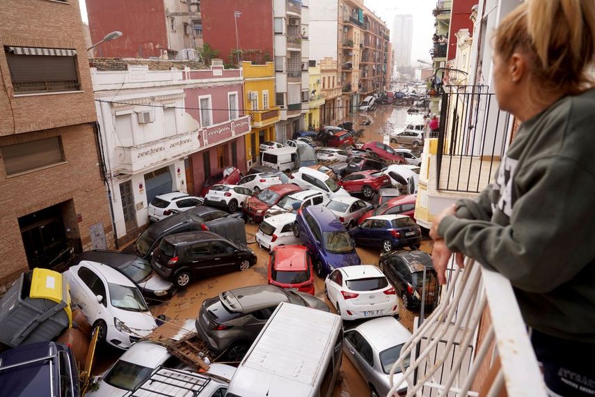 Una mujer mira por su balcón a los vehículos atrapados en la calle durante una inundación en Valencia, el miércoles 30 de octubre de 2024. 