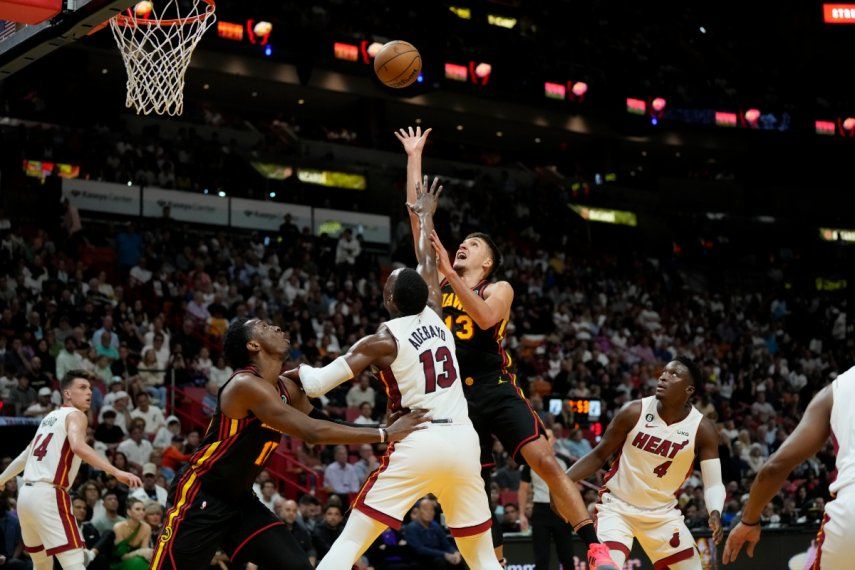 El escolta de los Atlanta Hawks, Bogdan Bogdanovic (13), pasa por encima de la defensa del centro del Heat de Miami, Bam Adebayo (13), durante la primera mitad de un partido de la NBA, el martes 11 de abril de 2023, en Miami.&nbsp;