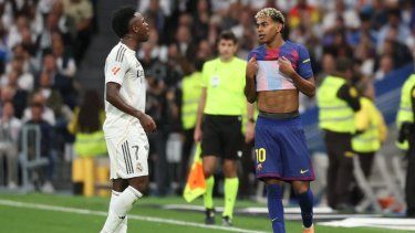 El delantero brasileño del Real Madrid, Vinicius Júnior (izq.), conversa con el delantero español del Barcelona, Lamine Yamal (izq.), durante el partido de la liga española entre el Real Madrid CF y el FC Barcelona en el estadio Santiago Bernabéu de Madrid, el 26 de octubre de 2025.&nbsp;