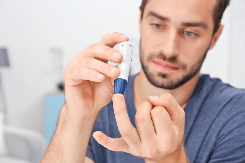 Un hombre utiliza un glucómetro para medir sus niveles de glucosa en sangre.