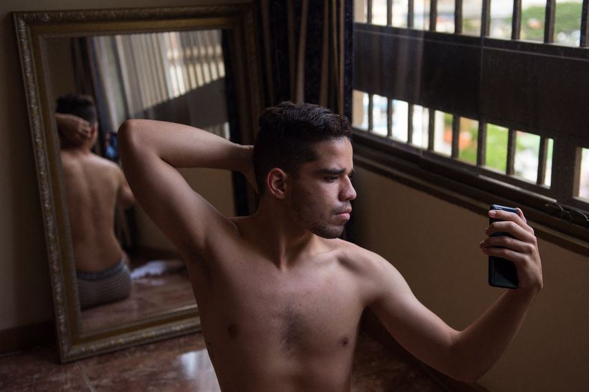 Brandon Mena se toma fotos en un espejo con su celular, para hacer contenido para su perfil de OnlyFans, en Caracas, el 12 de noviembre de 2020. Los jóvenes venezolanos utilizan el servicio de suscripción de contenido en inglés OnlyFans para superar la crisis económica.