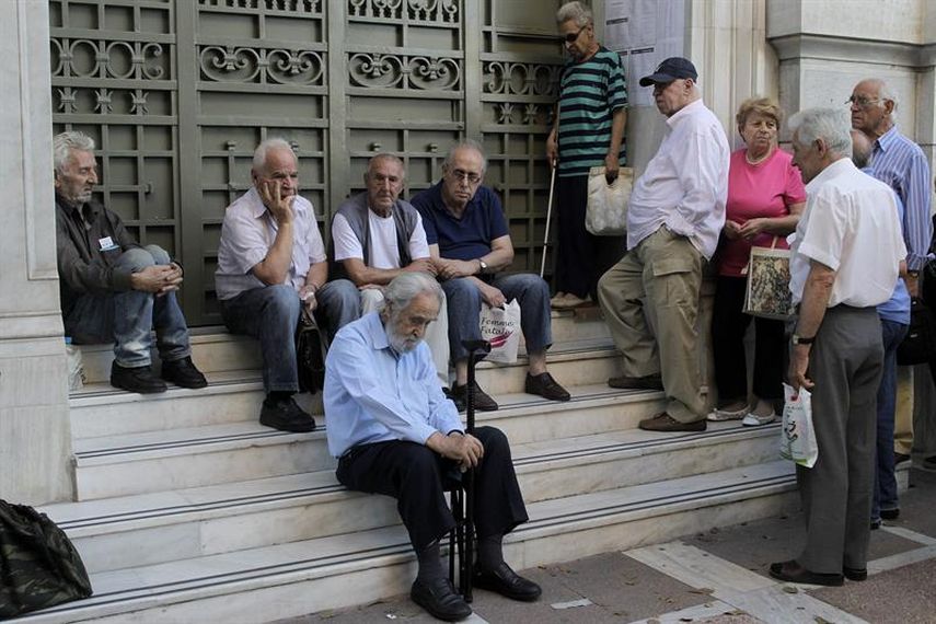 Pensionados que no poseen tarjeta de crédito esperan para cobrar a las afueras de una sucursal del Banco Nacional de Grecia en Atenas. (EFE) 