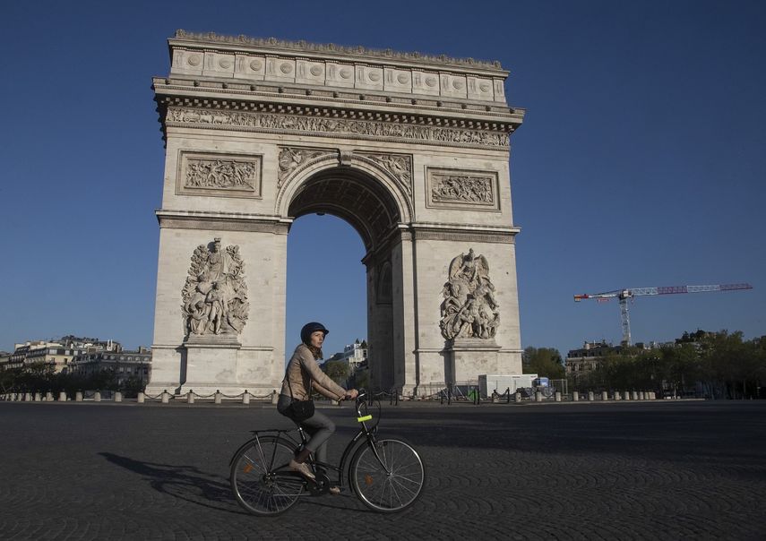 Una mujer pasa con su bicicleta frente a la Place Charles de Gaulle de Par&iacute;s el 14 de abril del 2020. La pandemia de coronavirus est&aacute; dando nuevo impulso a las bicicletas como alternativa al trasporte p&uacute;blico.&nbsp;
