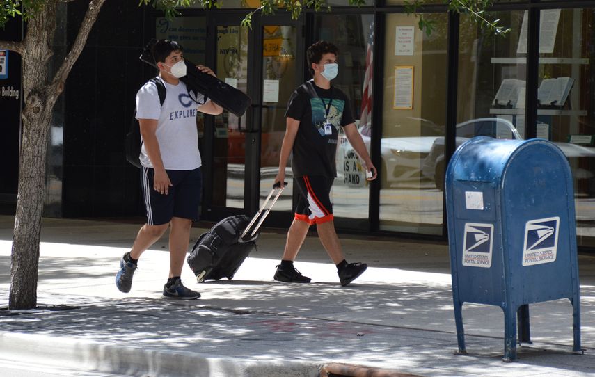 Dos jóvenes caminan por una calle de Miami, mientras se protegen del coronavirus.