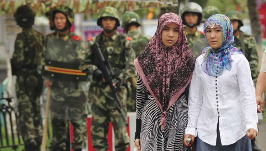 Mujeres de la etnia uigur vigiladas por militares chinos.