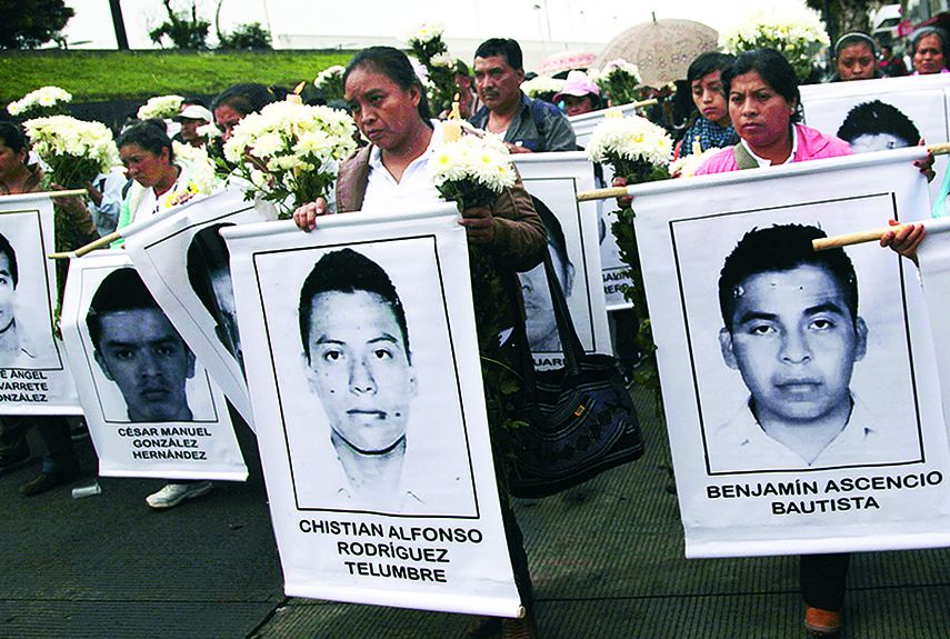 Familiares de los desaparecidos muestran fotos de los jóvenes para denunciar un suceso que ha conmovido al mundo. (AP)