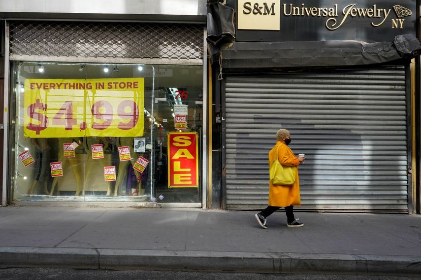 Una mujer camina frente a una tienda en liquidación.