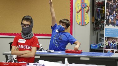 En esta imagen del martes 14 de julio de 2020, Aiden Trabucco utiliza una mascarilla para protegerse del coronavirus mientras levanta la mano para hacer una pregunta detr&aacute;s de Anthony Gonzales, durante un campamento de verano en la escuela secundaria Wylie, en Wylie, Texas.&nbsp;