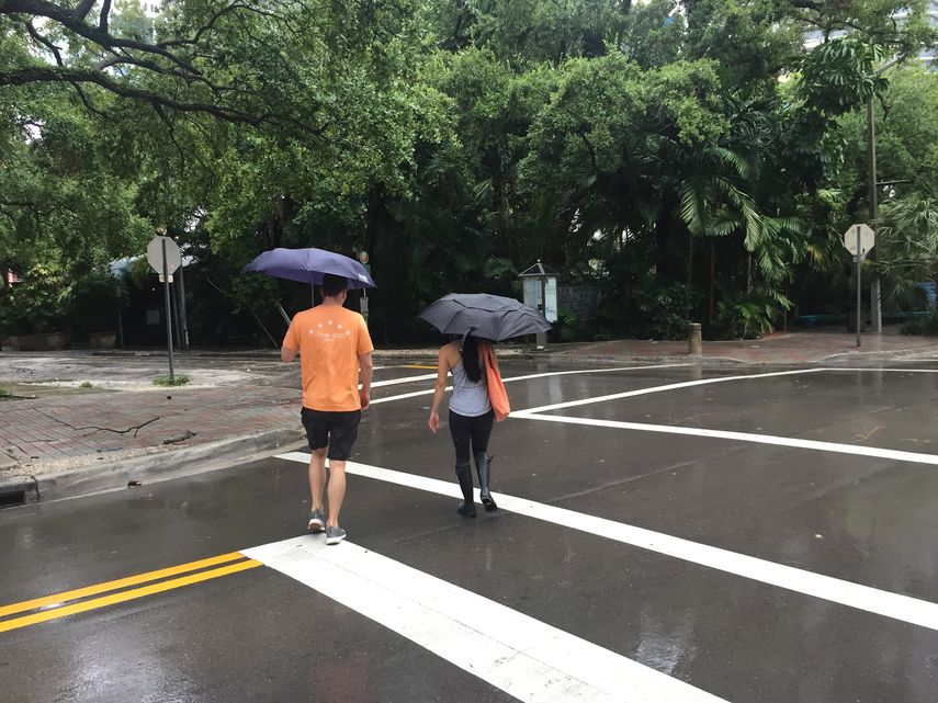 Un hombre y una mujer transitan por las calles desoladas de Miami, bajo la lluvia de la tormenta Gordon.