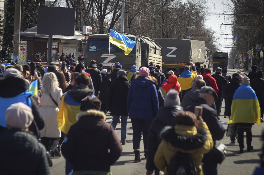 Personas con banderas ucranianas caminan hacia los camiones militares rusos durante una marcha contra la ocupación de Rusia, en Jersón, Ucrania, el domingo 20 de marzo de 2022.&nbsp;