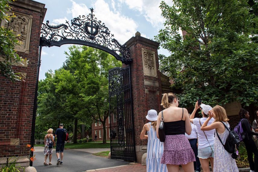 Un grupo de personas se toma fotos en la entrada de Harvard, en Cambridge, Massachusetts.