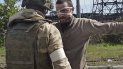 En esta imagen tomada de un video publicado por el servicio de prensa del Ministerio ruso de Defensa el miércoles 18 de mayo de 2022, un militar ruso registra a un soldado ucraniano después de que saliera de la asediada planta siderúrgica de Azovstal, en Mariúpol, Ucrania. 