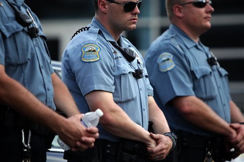 Agentes de la policía de Ferguson se forman para impedir el paso de los manifestantes congregados afuera de la delegación de policía durante una marcha en Ferguson ( Foto AP)