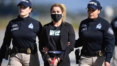 Nini Johana Usuga (C), hermana del narcotraficante Dairo Antonio Usuga, alias Otoniel, es escoltada por policías de Interpol antes de ser extraditada a EE. UU. en el Aeropuerto Internacional El Dorado, en Bogotá, Colombia, el 1 de julio de 2022.