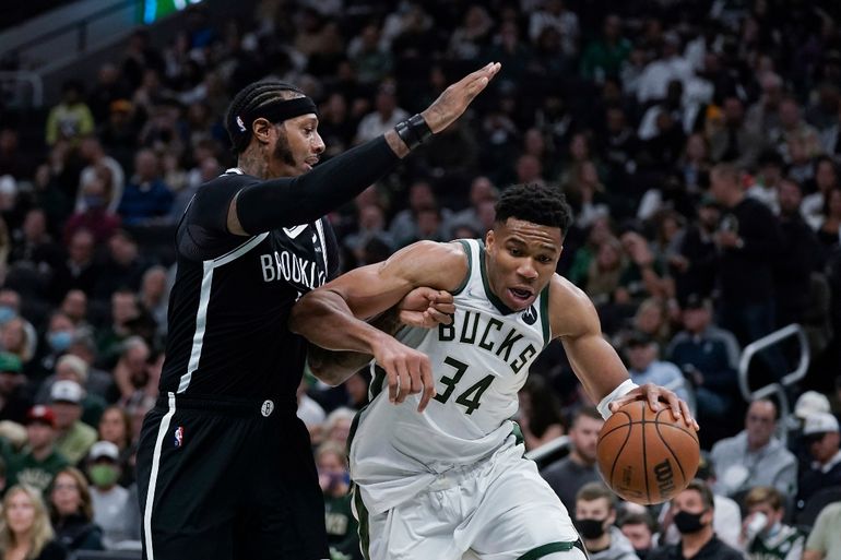 Giannis Antetokounmpo (34), de los Bucks de Milwaukee, es defendido por James Johnson, de los Nets de Brooklyn, durante la primera mitad del juego de la NBA, el martes 19 de octubre de 2021