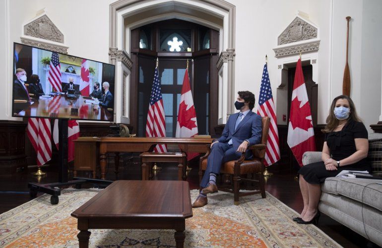 El primer ministro de Canadá, Justin Trudeau, y la viceprimera ministra y ministra de Finanzas, Chrystia Freeland, observan unas pantallas de televisión durante una reunión virtual con el presidente estadounidense Joe Biden, en su oficina en Ottawa, Canadá, el martes 23 de febrero de 2021. 