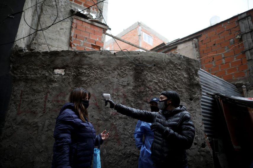 Una voluntaria toma la temperatura de una residente del barrio Fraga el sábado 6 de junio de 2020 durante una cuarentena ordenada por el gobierno para aplanar la curva del coronavirus, en Buenos Aires, Argentina.