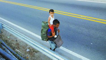 Un padre venezolano y su hijo recorren la vía hacía la ciudad de Bucaramanga desde Cúcuta.