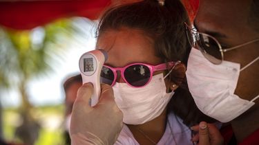 A una ni&ntilde;a con mascarilla para protegerse del nuevo coronavirus le toman la temperatura en un ret&eacute;n policial en la entrada de la provincia de La Habana, Cuba, en esta fotograf&iacute;a de archivo del lunes 10 de agosto de 2020.&nbsp;