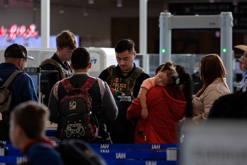 Un agente de ICE (Centro) revisa las identificaciones de los viajeros en el Aeropuerto Internacional George Bush, en Houston, Texas
