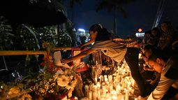 Una mujer enciende una vela mientras amigos y familiares rinden homenaje a las víctimas frente a la discoteca Jet Set en Santo Domingo el 12 de abril de 2025.