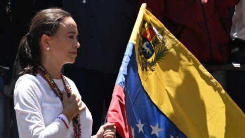 La líder opositora venezolana María Corina Machado sostiene una bandera nacional venezolana mientras hace un gesto desde lo alto de un camión durante una manifestación para protestar por los resultados de las elecciones presidenciales, en Caracas el 3 de agosto de 2024. 