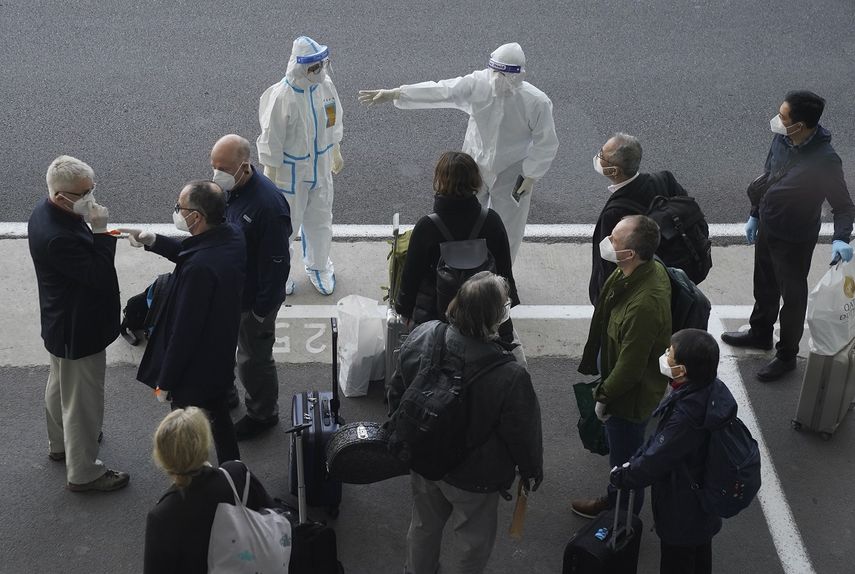 Un trabajador, equipado con un traje de protección, dirige a los miembros de un equipo de expertos de la Organización Mundial de la Salud a su llegada al aeropuerto de Wuhan, en la provincia de Hubei, en China, el 14 de enero de 2021.&nbsp;