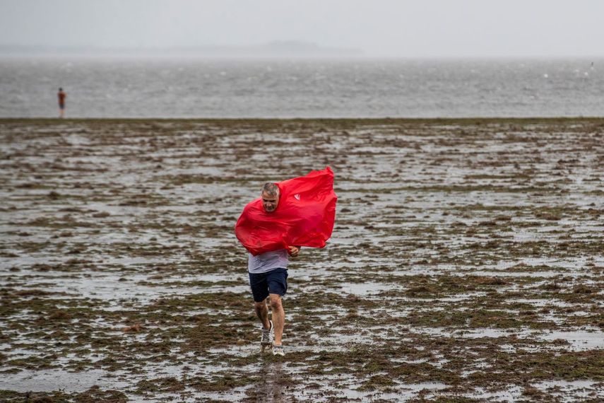 Dos personas caminan sobre el suelo expuesto de la bahía de Tampa debido a la marea baja y los intensos vientos generados por el huracán Ian, el miércoles 28 de septiembre de 2022, en Tampa, Florida.