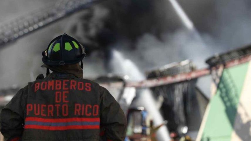 Uno de los agentes del Departamento de Bomberos de Puerto Rico participa en la extinción de un incendio.