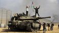 Palestinos ondean una bandera nacional y celebran junto a un taque de Israel destruido en la valla fronteriza que separa la Franja de Gaza de Israel, al este de Khan Younis, el 7 de octubre de 2023.
